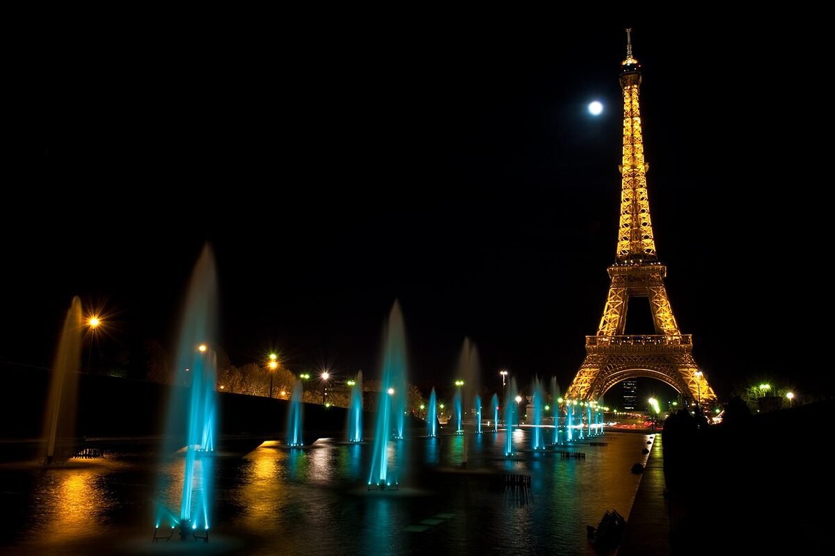 The Eiffel Tower illuminated at night, seen from the Trocadéro fountains in Paris